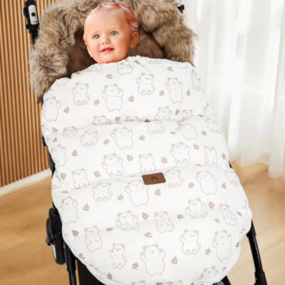 bébé dans chanceliere poussette avec motifs ourson blanc qui sourit.