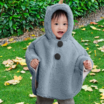 enfant qui sourit porte jolie poncho bébé pompon bleu
