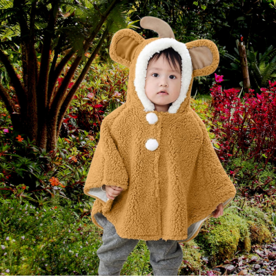 bébé dans jardin avec poncho bébé pompon or