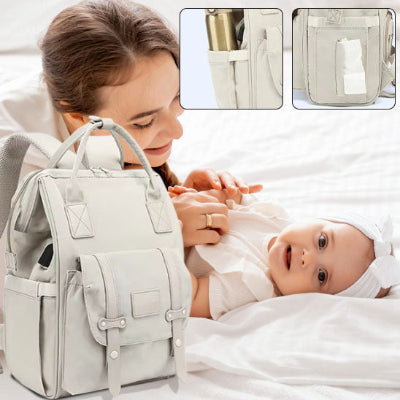 Maman regarde bébé allongé sur lit à côté de sac a langer bebe poupie.